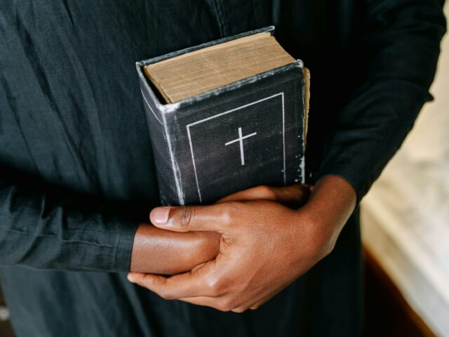 Pessoa religiosa segurando um livro com uma cruz